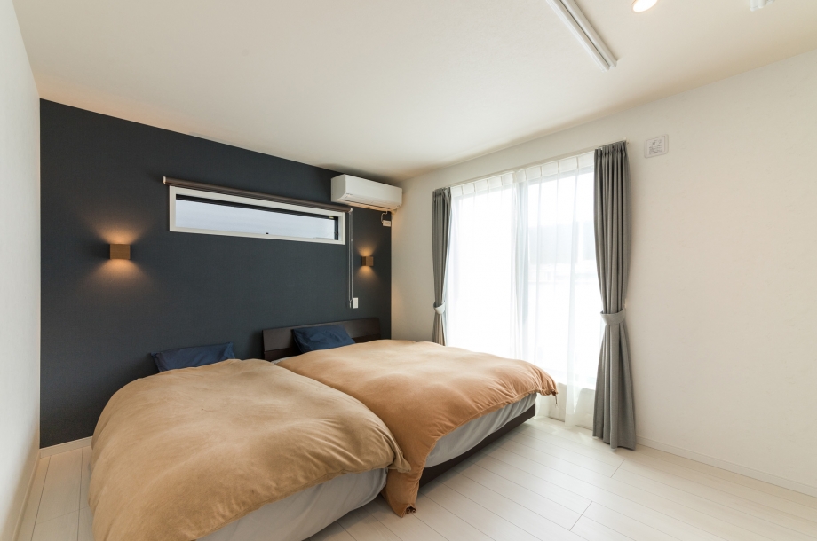 ネイビーのアクセントクロスが落ち着いた雰囲気の寝室。照明やコンセントなども使いやすい位置にあり、リラックスして使えそうです。