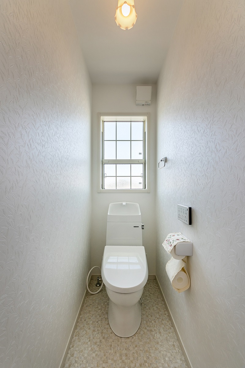 大きな上げ下げ窓から明るい陽射しが差し込むトイレ。<br />
カントリー調の照明や可愛いペーパーホルダーカバーが印象的です。
