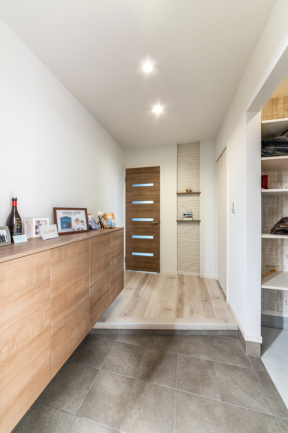 白を基調とした洗練された玄関。<br />
フロートタイプのシューズボックスと土間収納を設置し、玄関周りをスッキリとした空間に。