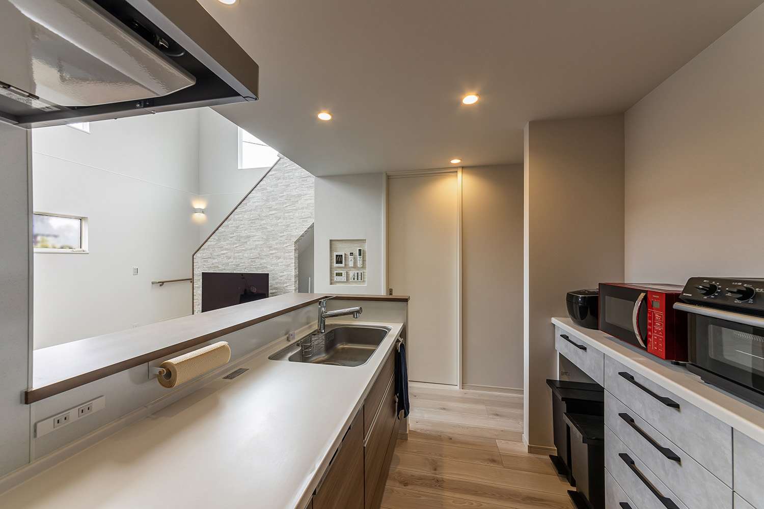 使い勝手の良い対面式キッチン。<br />
真っ白な天板と木目調のキッチンが清潔感と温もりをプラスします。<br />
腰壁を設置し、調理中の手元を隠したり、油や水はねを防止したりと、機能性も◎。<br />