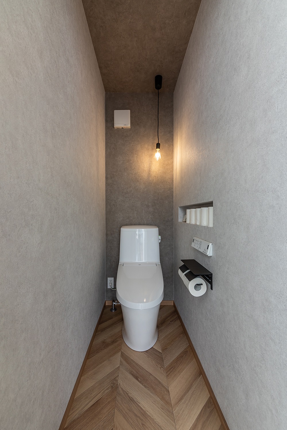 上品な色合いのフレンチヘリンボーン柄の床が可愛いトイレ。<br />
ニッチを設置し、スッキリとした収納を実現しました。