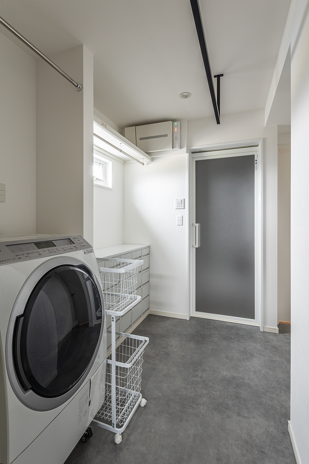 脱衣室は、石目調のフロアがモダンな印象を与えます。<br />
ハンガーパイプを3本設置したことで、ご家族の洗濯物をまとめて干せる、広々としたランドリースペースになりました。