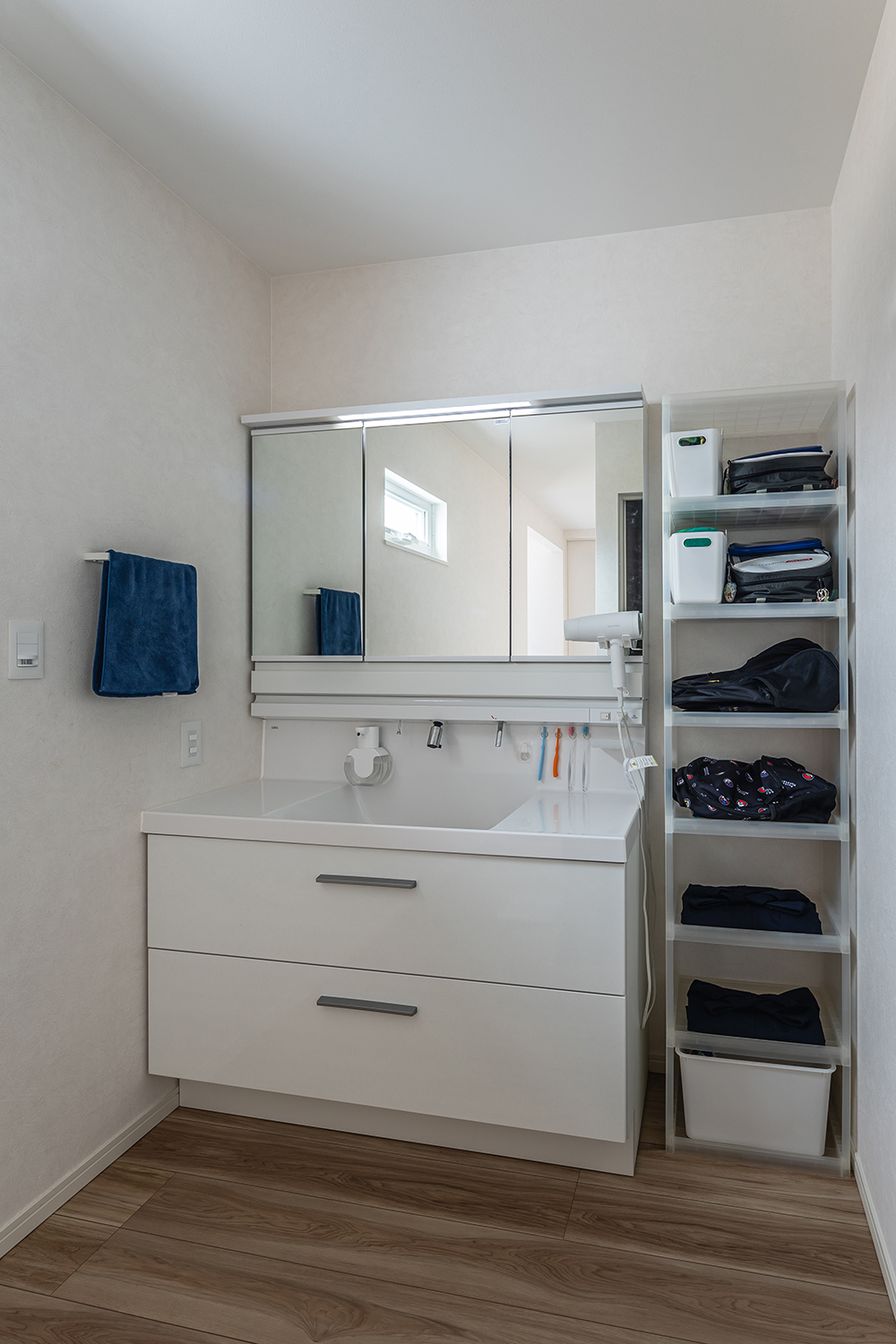 シンプルな印象の洗面室は、帰宅後すぐにカバンが置ける収納棚を設置。<br />
日々の暮らしをより便利にしました。