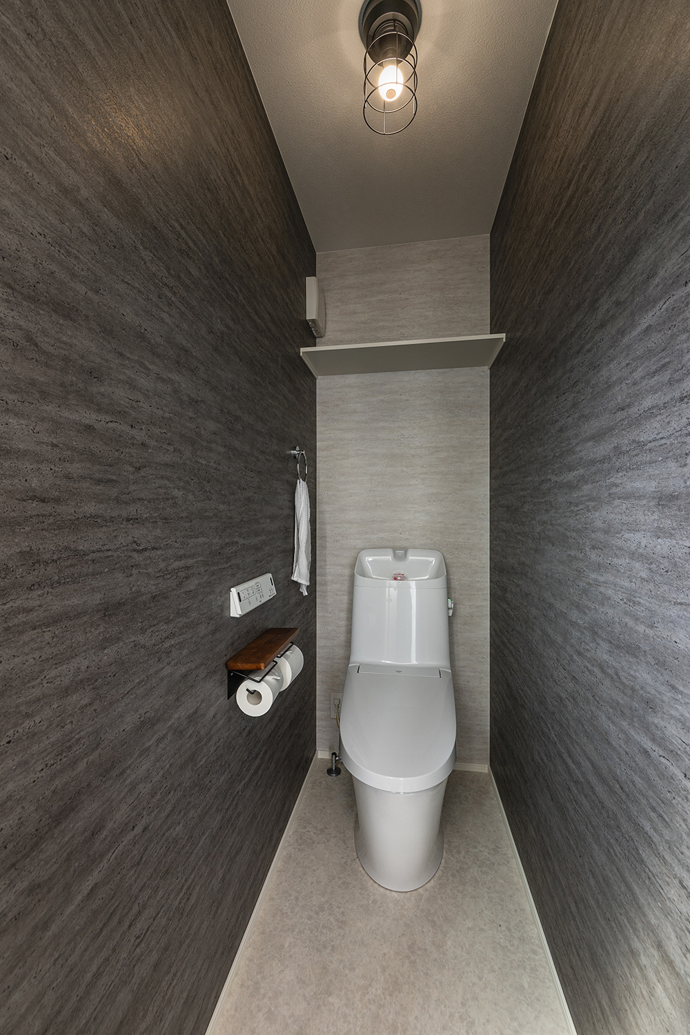 モダンな壁紙が特徴的な2階のトイレ。<br />
格子状のかっこいい照明との組み合わせでシックに仕上げました。