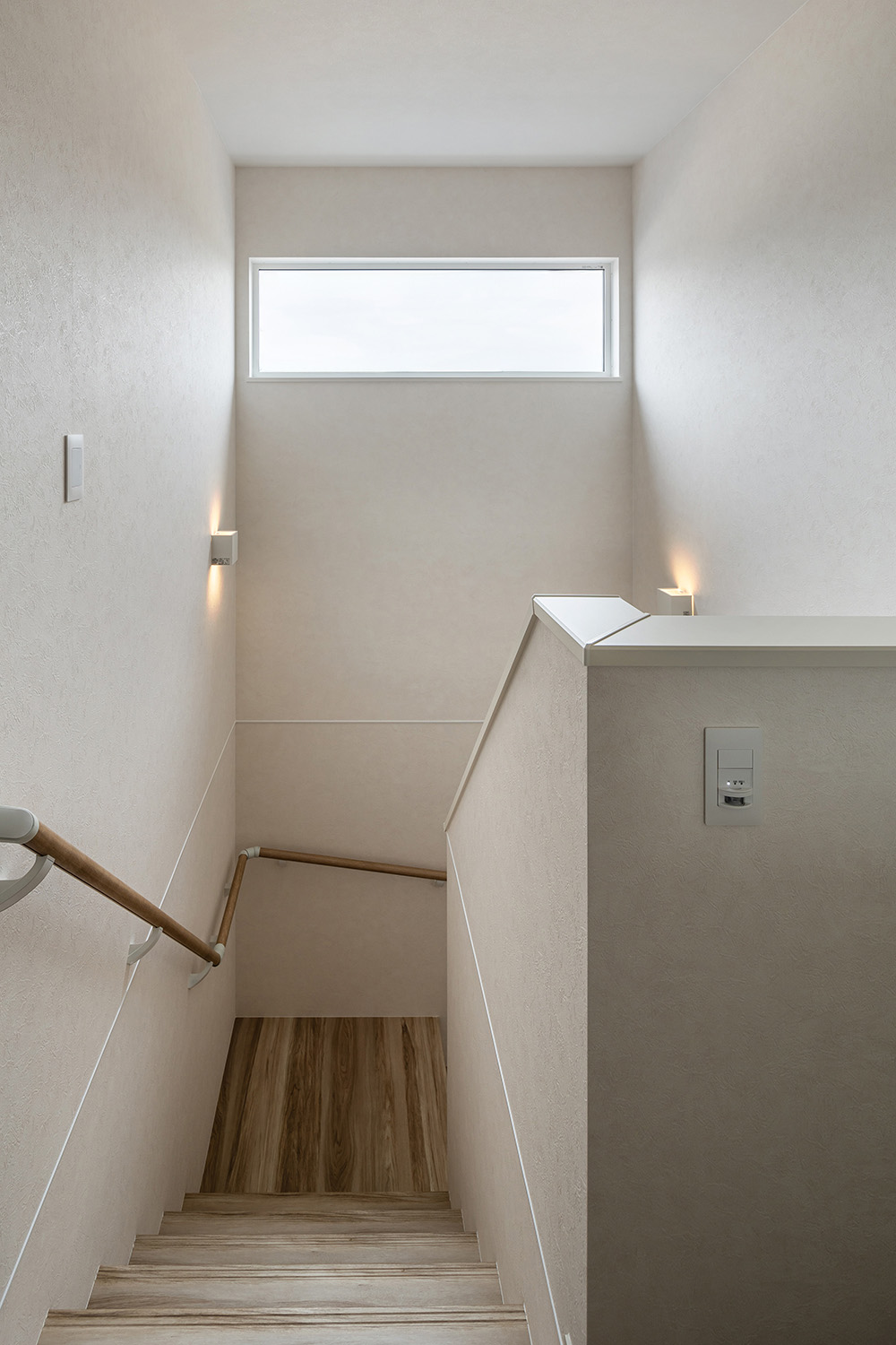 ブラケットライトの柔らかな光が印象的な階段は、大きな窓を設置し、いつでも明るく開放的な空間を演出します。
