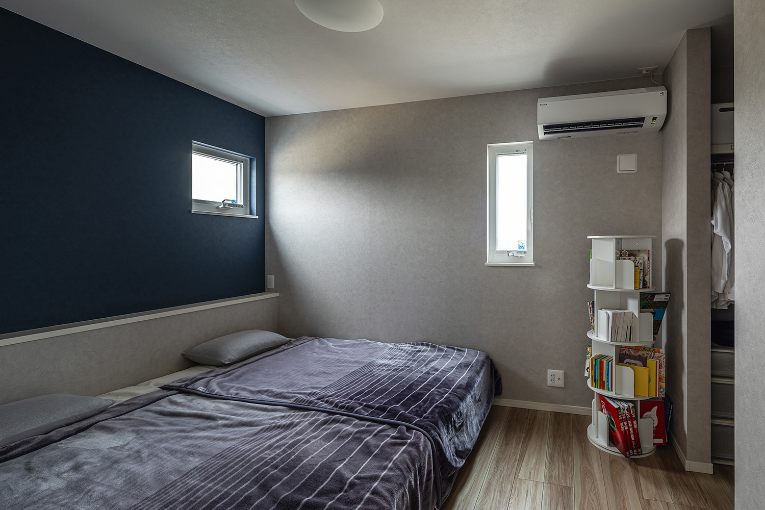 石目調のグレーのクロスとネイビーのアクセントクロスが、モダンな印象を与えます。<br />
部屋の奥にウォークインクローゼットを設けたことで、身支度もスムーズに行える、快適で便利な寝室になりました。