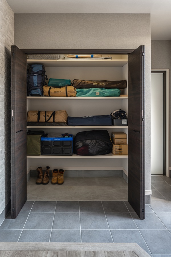 すっきりとしたシンプルモダンな玄関。シューズボックスやサッシをウォールナットで統一することで、空間全体に落ち着きと高級感をもたらしています。<br />
約1帖の土間収納には可動棚を設置し、ライフスタイルに合わせた高い収納力とデザイン性を両立させました。