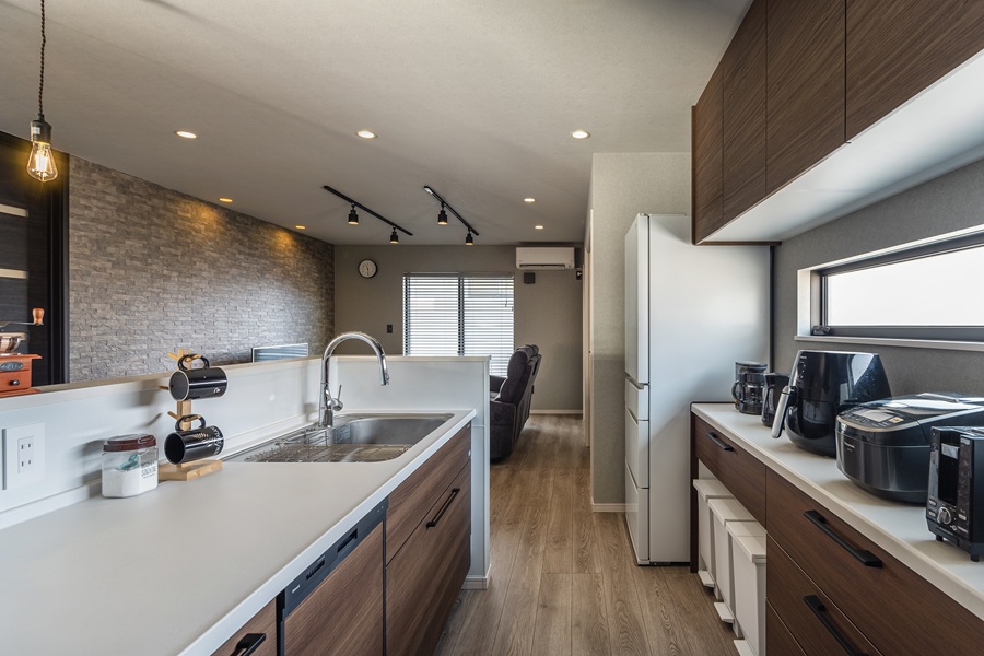 温かみのある木目調のデザインに、清潔感あふれる白い天板を組み合わせた、すっきりとした佇まいのキッチン。<br />
キッチンカウンターの下にはゴミ箱専用の収納スペースを設け、生活感を感じさせないスマートなキッチンを実現しました。