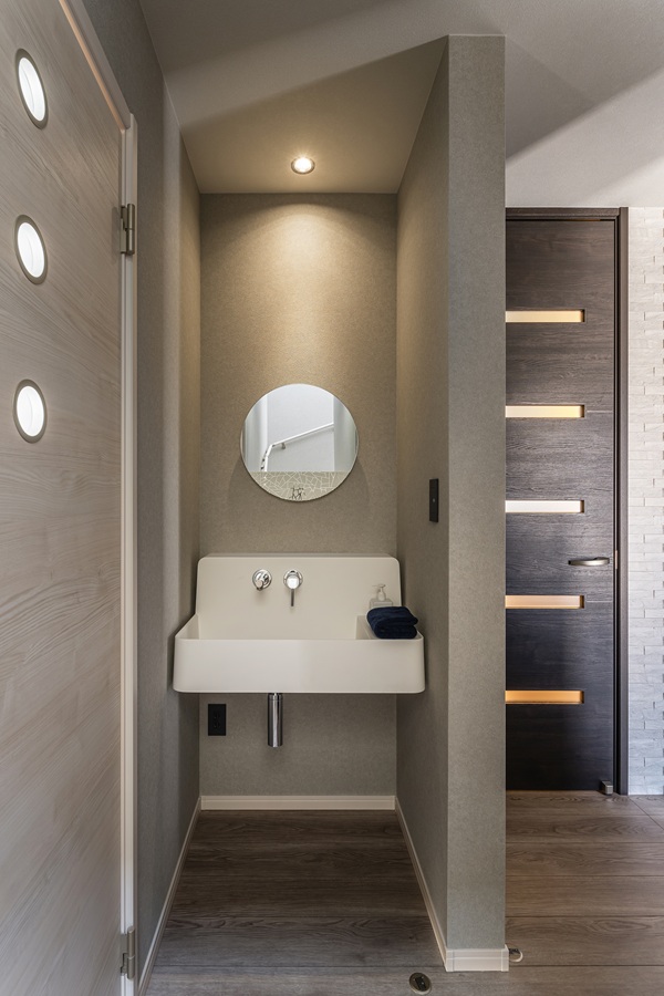 玄関ホールの一角には、帰宅してすぐに手を洗える便利な独立洗面台を設置。<br />
使い勝手の良いシンプルなデザインに、柔らかな印象を与える丸型ミラーを組み合わせることで、空間におしゃれなアクセントを添えています。